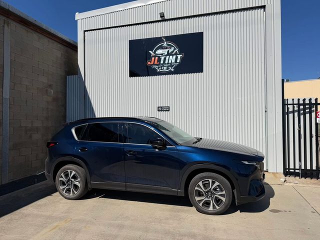 Dark blue Mazda CX-5 with premium window tint, parked outside the JL Tint shop