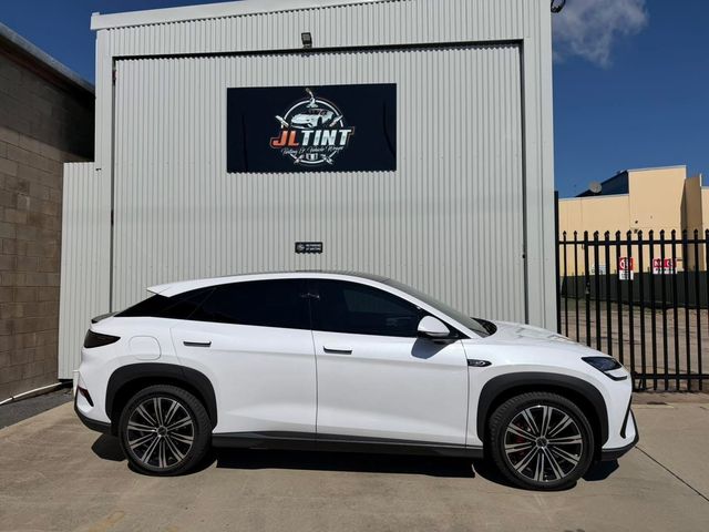 White SUV with premium window tint, parked outside the JL Tint shop