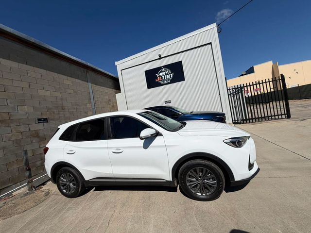 White SUV with premium window tint, parked outside the JL Tint shop